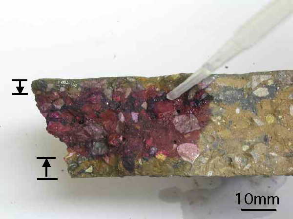 Phenolphthalein indicator solution applied to a fresh fracture surface through a concrete slab.